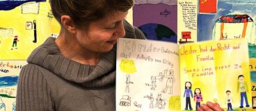 Eine Frau zeigt ein Buch mit Kinderzeichnungen.