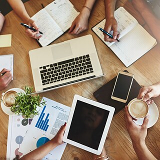 Tisch mit Tablet, Laptop und Händen