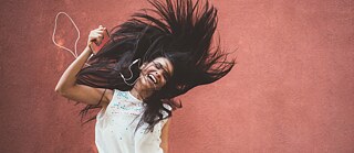 Frau hört Musik und schüttelt die Haare