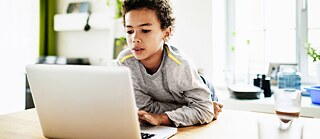 Ein Junge macht am Laptop seine Hausaufgaben