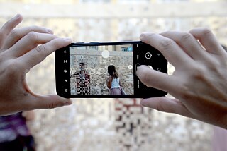 Bir cep telefonunu tutan iki el duvarın fotoğrafını çekiyor.