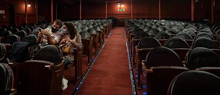 Espectador y espectadora con mascarilla solos en la sala Cándido Lara del Teatro Lara de Madrid.