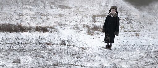 Ein Junge steht auf einer mit Schnee zugedeckter Landschaft
