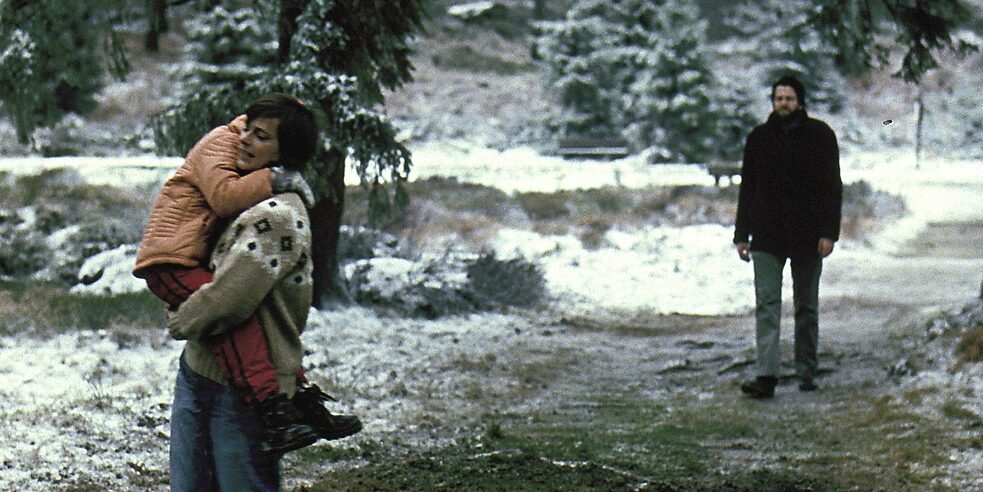 Frau mit Kind auf dem Arm und Mann im Wald (Ausschnitt)