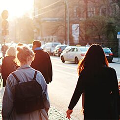 Хора вървят по улица по залез слънце