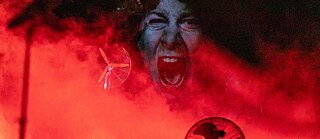 Et billede fra teaterforestillingen "Tornado". Der ses et ansigt, som skriger på rødt baggrund.