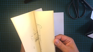 Comic artist flipping through a dummy of a comic zine.
