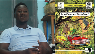 Man in white shirt laughing, while the right side of the screen is showing a comic book cover of a car in a jungle.