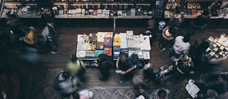 Billede af mennesker på et bibliotek. Nogle af dem er lidt slørede.