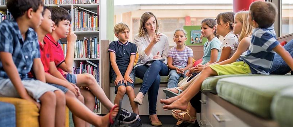 Lehrerin mit Schüler*innen im Kreis
