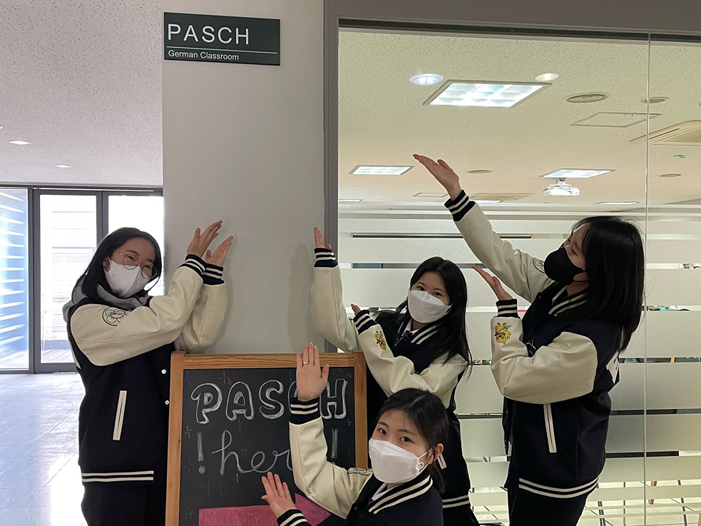 4명의 여학생들이 PASCH 표지판 앞에 서있다. 