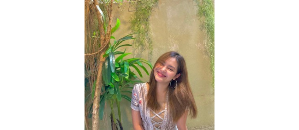 Lächelnde junge Frau neben einer Pflanze