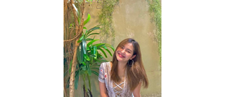 Smiling young woman next to a plant