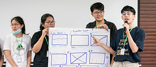 Vier Schülerinnen und Schüler präsentieren einen Entwurf