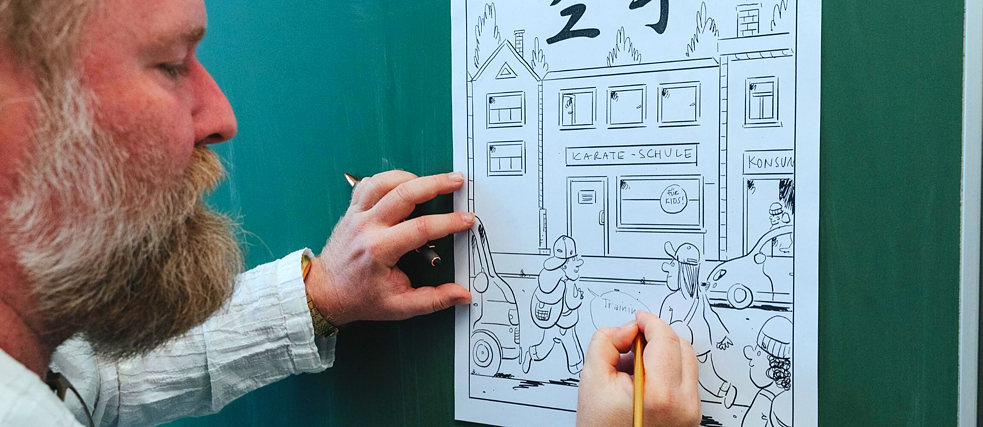 Der Künstler Mamei beim Zeichnen eines Comics