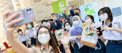 A teacher takes a selfie with her smartphone. In the background you can see some students and the team of the Goethe-Institut waving into the camera.