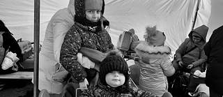 Schwarzweißfoto eines Kleinkindes und eines kleinen Mädchens in Winterjacken