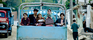 Fotograma Almanya. Dos adultos y tres niños viajan en camión