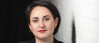 Die Autorin Nino Haratischwili steht an einer Wand vor einem schwarzen Raum.