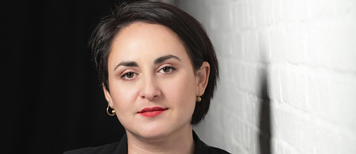 Die Autorin Nino Haratischwili steht an einer Wand vor einem schwarzen Raum.