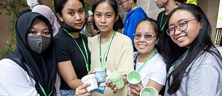 Fünf Personen halten kleine Blumentöpfchen in die Kamera und lachen.