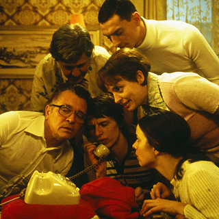 Mehrere Personen beugen sich über einen Telefonhörer.