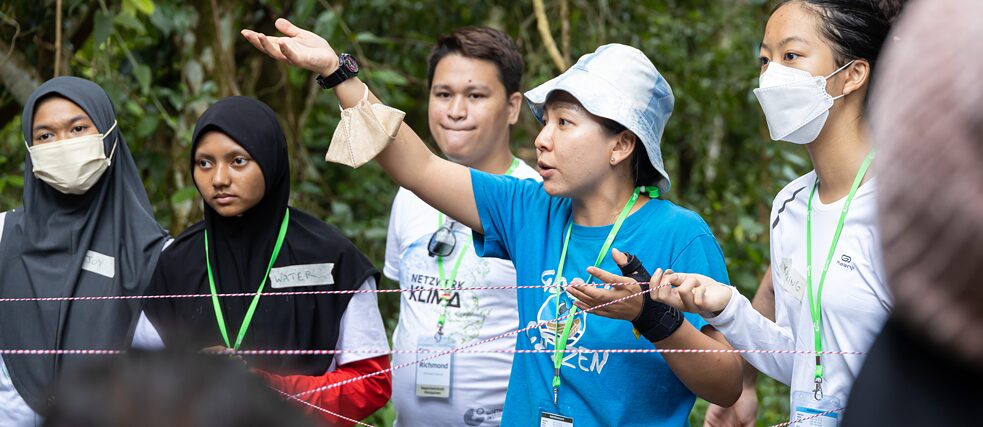 Workshopleiter in blauem T-Shirt leitet eine Gruppe an.