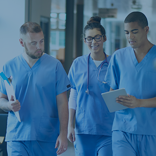 Drei Pflegekräfte schauen sich ein Krankenblatt an während laufen