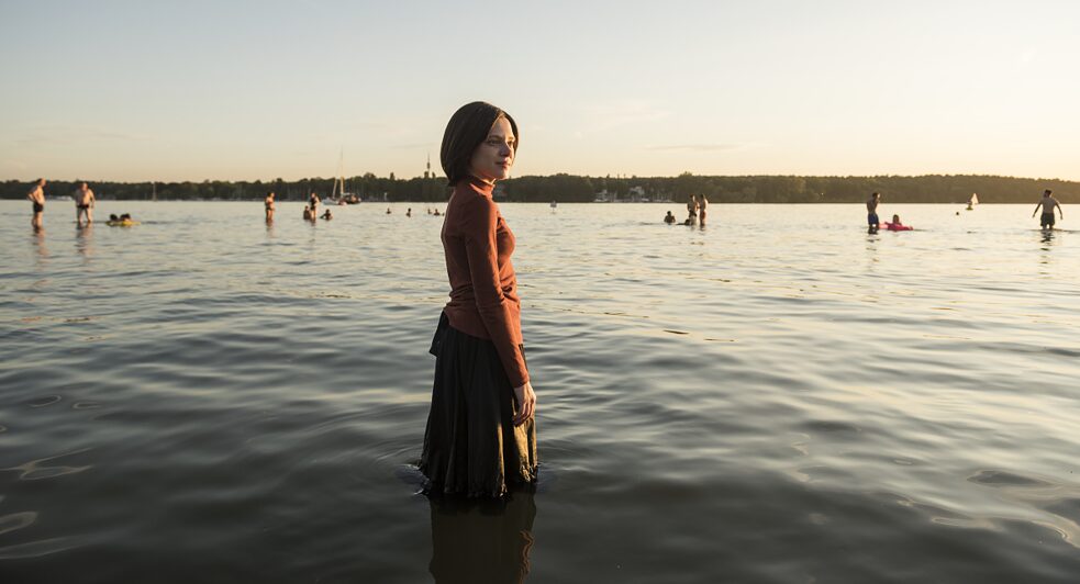 A protagonista da série NADA ORTODOXA, Esther Shapiro (Shira Haas), apelidada de Esty, mergulha até os joelhos no lago Wannsee, em Berlim.