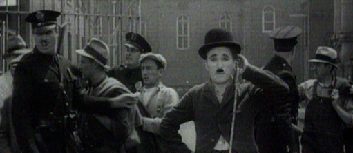 Film still with Charlie Chaplin surrounded by striking workers in a struggle with police