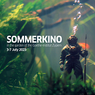 A diver figurine in an aquarium surrounded by goldfish and water plants. Air bubbles rise from the figurine.