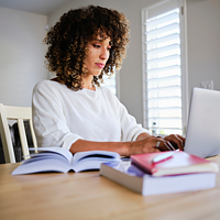 Woman sitting at desk with books and computer