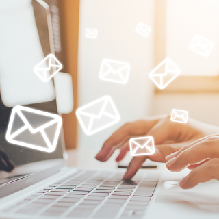 Eine Person sitzt am Laptop, kleine Briefsymbole schweben in der Luft