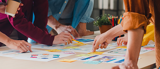 Group of collagues pointing at post its on table