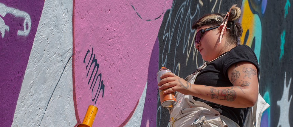 Künstlerin arbeitet an ihrer Street Art mit einer Spray-Dose
