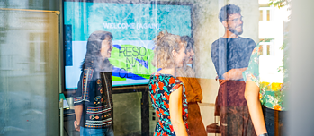 Hinter einer Glasscheibe stehen Teilnehmende von Resonance und nehmen an einem Workshop teil.