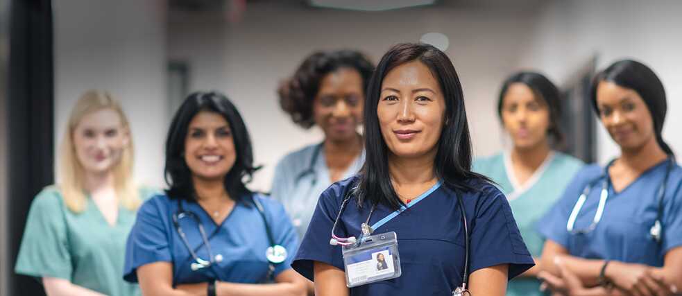 Mehrere Krankenpflegerinnen schauen selbstbewusst in die Kamera. 
