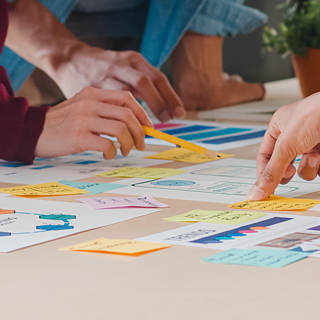 Group of collagues pointing at post its on table