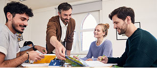 Vier Personen sitzen an einem Tisch und interagieren freudig