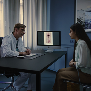 Eine Frau sitzt bei einem Gynäkologen im Besprechungsraum.