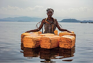 A woman standing in the water with yellow plastic water containers swimming around her.  &copy; Pamela Tulizo Enfer Paradisique, 2021