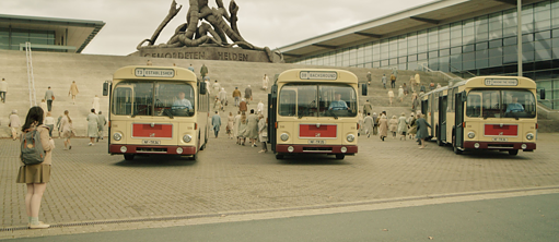 Una mujer delante de tres autobuses.