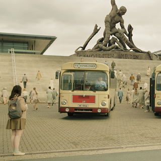 Eine Frau steht vor drei Bussen.