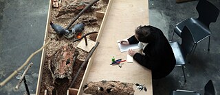 Zwei graue Papageien spielen mit einem Ast in Zusammenarbeit mit einem Künstler, der schreibt