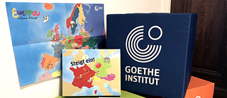 Cube siège en vert, orange et bleu avec logo Goethe et jeu Monte à bord
