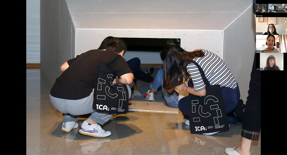 在这张“隐藏计划”圆桌谈的视频截图中，右侧是参会嘉宾的讲话窗口，左侧是讲者的幻灯片，展示了两位参观者蹲在矮门前的场景。该圆桌谈是“隐藏计划”工作坊的阶段性总结，由“生而不同 我就是我”——DAWA国际无障碍文化节呈现，合作机构包括OCAT上海馆、德国驻上海总领事馆文化教育处和加拿大驻上海总领事馆