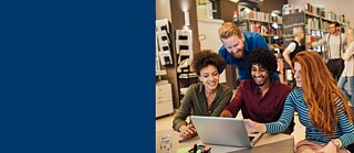 Trois étudiants regardent un ordinateur portable. Ils rient et discutent de leurs devoirs.
