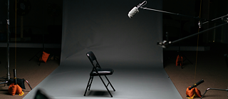 Foto: Ein leerer Stuhl steht mitten in einem Studio. Ein Mikrofon ist auf den leeren Stuhl gerichtet. 