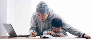 A father works on the computer and looks after his son at the same time