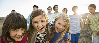 Fröhliche Jungen und Mädchen umarmen sich und blicken grinsend in die Kamera